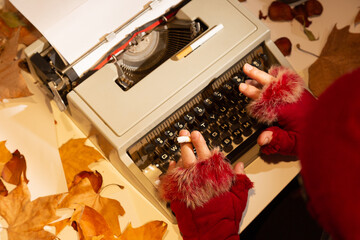 Manos de escritora con frío y fumando sobre la máquina de escribir - obrazy, fototapety, plakaty