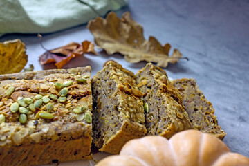 Vegan pumpkin pie with honey, poppy seeds and dried fruits. Homemade cupcake  sugar free cut into pieces on a white table, close-up