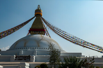 The Bouddhanath Temple in Kathmandu, Nepal. The temple has many colourful prayer flags with 'om mani padme hum' mantra written on them attached to it's golden rooftop. Spirituality and meditation.