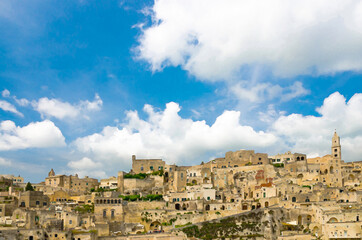 Fototapeta na wymiar Watercolor drawing of Sassi di Matera panoramic view of historical centre Sasso Caveoso of old ancient town with rock cave houses in front of blue sky and white clouds, Basilicata, Southern Italy