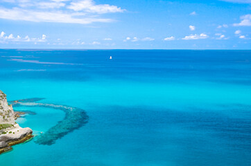 Obraz premium Watercolor drawing of Aerial view of beautiful amazing Tyrrhenian sea with turquoise water, tropical seascape with blue sky white clouds, small yacht background, Tropea, Calabria, Southern Italy