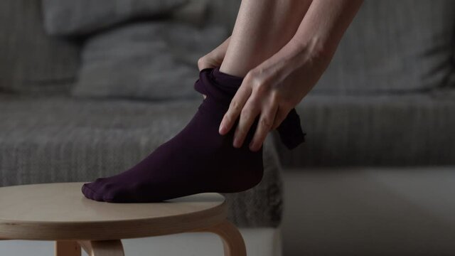 Pretty woman pulling up a purple tight on her legs, getting ready and dressed.