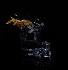 Splashing drink on a black background with a physalis
