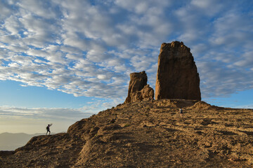 Traveler photographing a giant stone in the mountains during sunset.