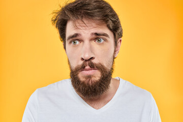 Fototapeta premium Man with emotional expression white t-shirt close-up studio yellow background