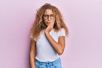 Beautiful caucasian teenager girl wearing white t-shirt over pink background touching mouth with hand with painful expression because of toothache or dental illness on teeth. dentist