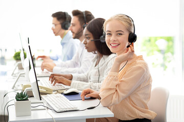 Team of diverse hotline operators with headphones providing service to clients at call center