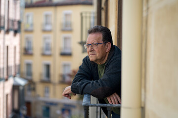lifestyle portrait of sad and depressed mature man 65 to 70 years old at home balcony feeling lonely and confused facing getting old and retirement alone looking away thoughtful