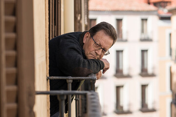 lifestyle portrait of sad and depressed mature man 65 to 70 years old at home balcony feeling lonely and confused facing getting old and retirement alone looking away thoughtful