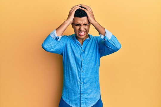 Young arab man wearing casual clothes suffering from headache desperate and stressed because pain and migraine. hands on head.