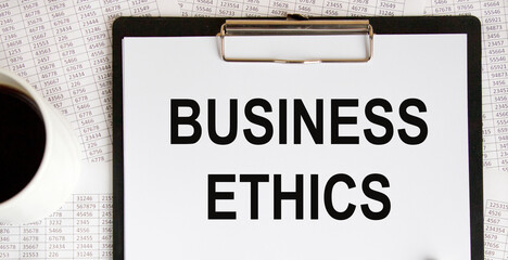 Text BUSINESS ETHICS, a number of accounting reports and a mug of coffee.