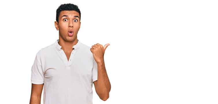 Young arab man wearing casual clothes surprised pointing with hand finger to the side, open mouth amazed expression.