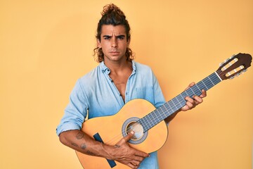 Young hispanic man playing classical guitar skeptic and nervous, frowning upset because of problem. negative person.