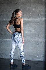 Fototapeta na wymiar Fitness woman in sportswear posing in gym full length.