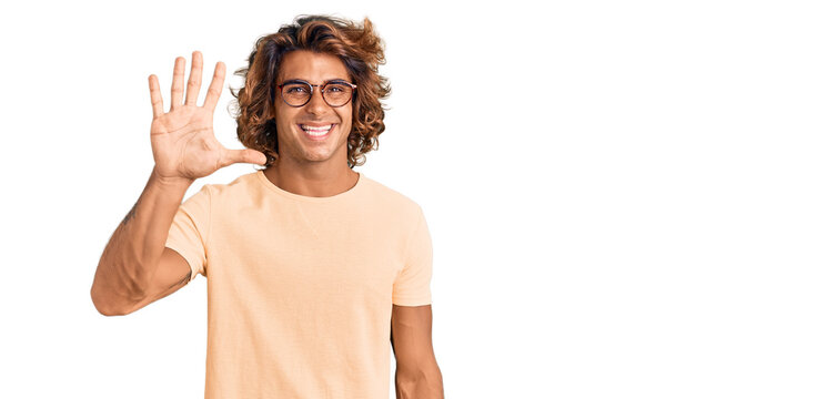 Young hispanic man wearing casual clothes and glasses showing and pointing up with fingers number five while smiling confident and happy.