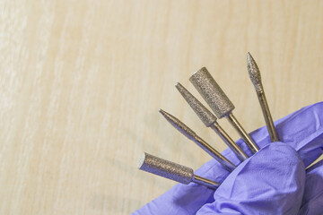 Set of milling cutters in a manicurist hand on wood background and some free space for text....