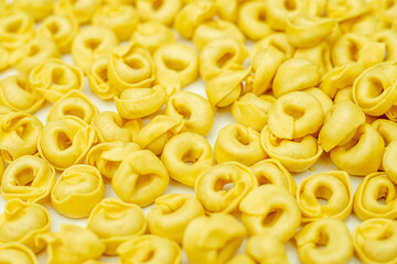 Close-up photo. Background of dried tortellini. Full frame pattern. Italian dumplings made from unleavened dough with meat, cheese or vegetables. Traditional Italian dish.