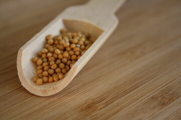 Grains of mustard on a wooden spoon.