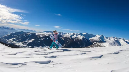 Fotobehang A woman walking on powder snow with her snowboard on top of Katschberg in Austria. Panoramic view on the surrounding mountains. Winter wonderland, Clear and sunny winter day. Free ride. © Chris
