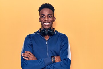 Fototapeta na wymiar Young african american man wearing sportswear and headphones happy face smiling with crossed arms looking at the camera. positive person.