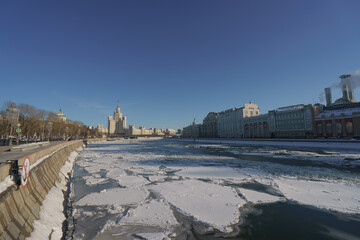Moscow cityscape in winter sunny day. Stalinist skyscraper, Moskva river had been covered by ice floes. Kotelnicheskaya emb.Thermal Power Station in Raushskaya embankment. Bolshoy Ustinsky Bridge.