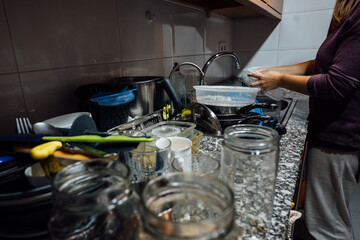 girl washing a mountain of dishes in the kitchen