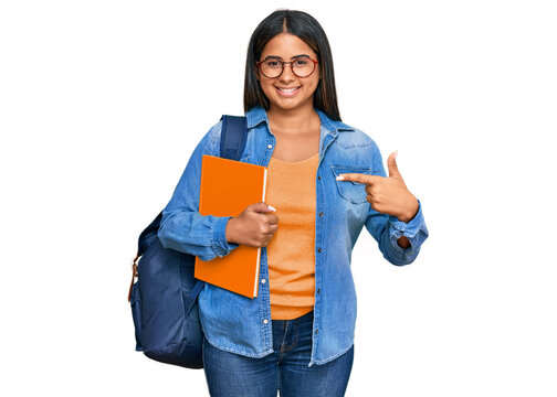 Young latin girl wearing student backpack and holding books cheerful with a smile on face pointing with hand and finger up to the side with happy and natural expression