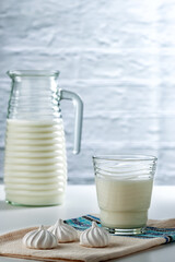 Natural whole milk in a jug and glass with bizet on a white brick wall background