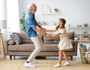 Grandfather dancing with granddaughter at home.