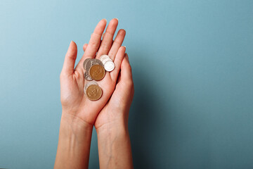 Woman's hands holding a heap of coins background, top view, with copy space