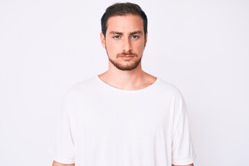 Fototapeta premium Young handsome man wearing casual white tshirt skeptic and nervous, frowning upset because of problem. negative person.