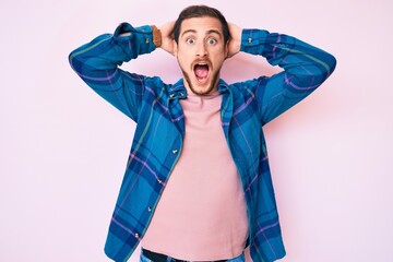 Young handsome man wearing casual clothes crazy and scared with hands on head, afraid and surprised of shock with open mouth