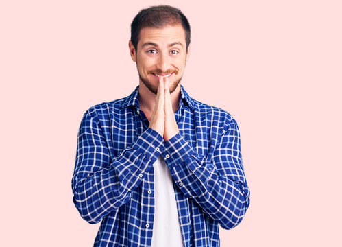 Young handsome caucasian man wearing casual clothes praying with hands together asking for forgiveness smiling confident.