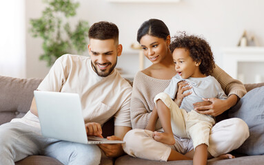 Diverse family using laptop on sofa together.