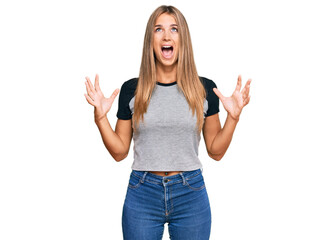 Fototapeta na wymiar Young blonde woman wearing casual clothes crazy and mad shouting and yelling with aggressive expression and arms raised. frustration concept.