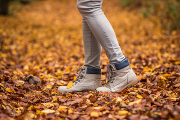 Walking with hiking boot in autumn leaves on footpath at forest