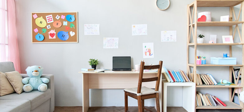 School child room interior space with table, couch, bookcase, books and laptop on table indoors at home apartment background. Children homeschool, online distance remote virtual learning, banner.