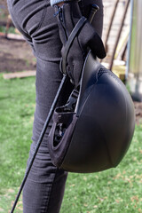 Woman in black gloves holding horse back riding helmet and whip in her hands. Equestrian equipment