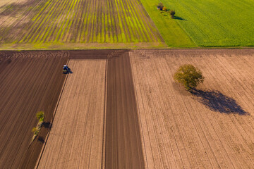 Verschiedene Farben von Feldern und Äcker mit einem Traktor sowie verschiedenen Bäumen und...