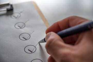 Abhaken einer Checkliste mit Kugelschreiber auf einem grauen Schreibtisch