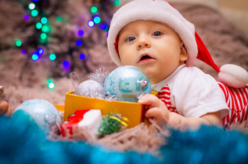baby in santa hat with christmas balls