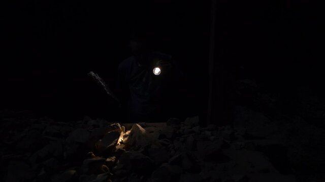 Person in old silver mine looking at rocks.