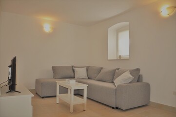 Mali Losinj, Croatia 2020.Modern, stylish living room in grey color with window. Interior design of modern grey living room furniture against white wall with a lamps on wall and lots of copy space.