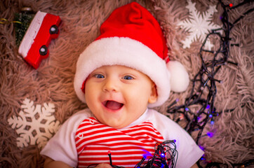 baby in santa claus hat with Christmas toys.