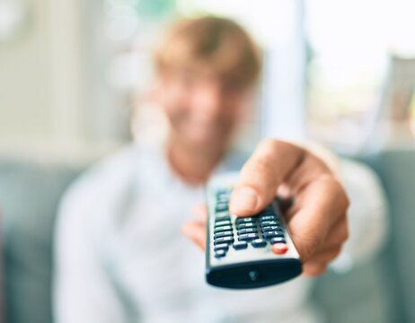 Close up of middle age handsome caucasian man using tv control