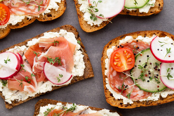 Sandwich with cereals bread and salami on dark marble background.
