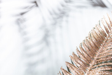 Gold palm leaves and shadows on a blue wall background.