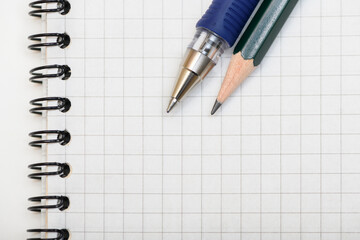 Pen and lead pencil on blank page of the notebook. Top view.