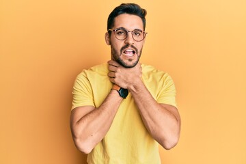 Fototapeta premium Young hispanic man wearing casual clothes and glasses shouting and suffocate because painful strangle. health problem. asphyxiate and suicide concept.