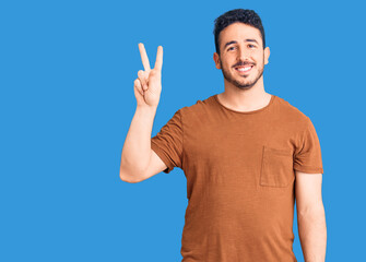 Naklejka premium Young hispanic man wearing casual clothes showing and pointing up with fingers number two while smiling confident and happy.